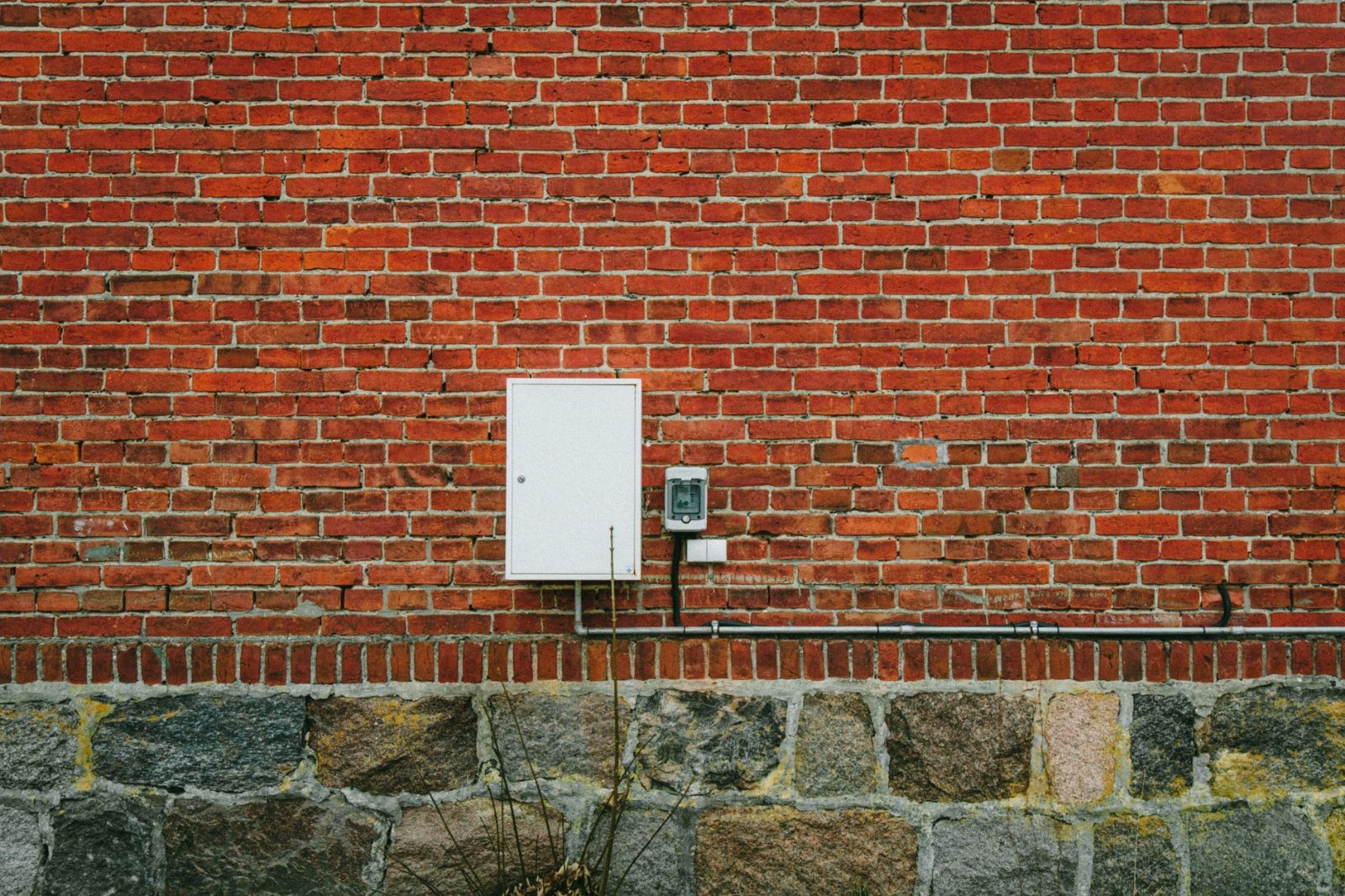 The exterior half of the same kind of job: an installed meter set on common brick with its riser conduit strapped